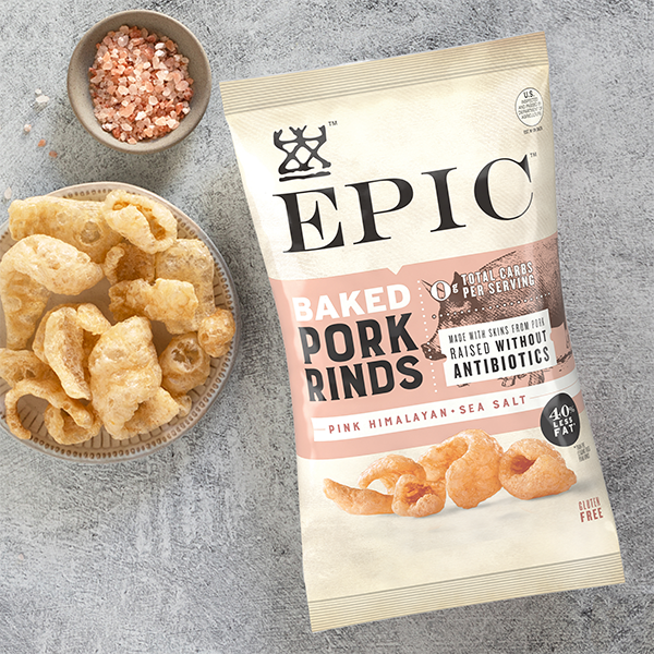 EPIC Provisions' Pink Himalayan Sea Salt Baked Pork Rinds in brand new packaging on a textured table with a bowl of pork rinds and pink Himalayan sea salt next to it.