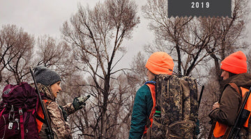 three women wearing hunting gear plan as they head on to their next hunt