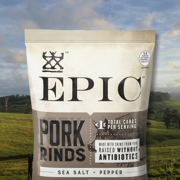 A close up image of a bag of EPIC Provisions Sea Salt and Pepper Pork Rinds. The background image is a farm landscape scene. 